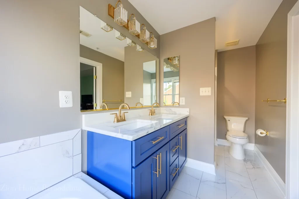 Blue double sink vanity with quartz top, champagne fixtures, and marble-look flooring by bathroom remodeler in Silver Spring, MD, US.