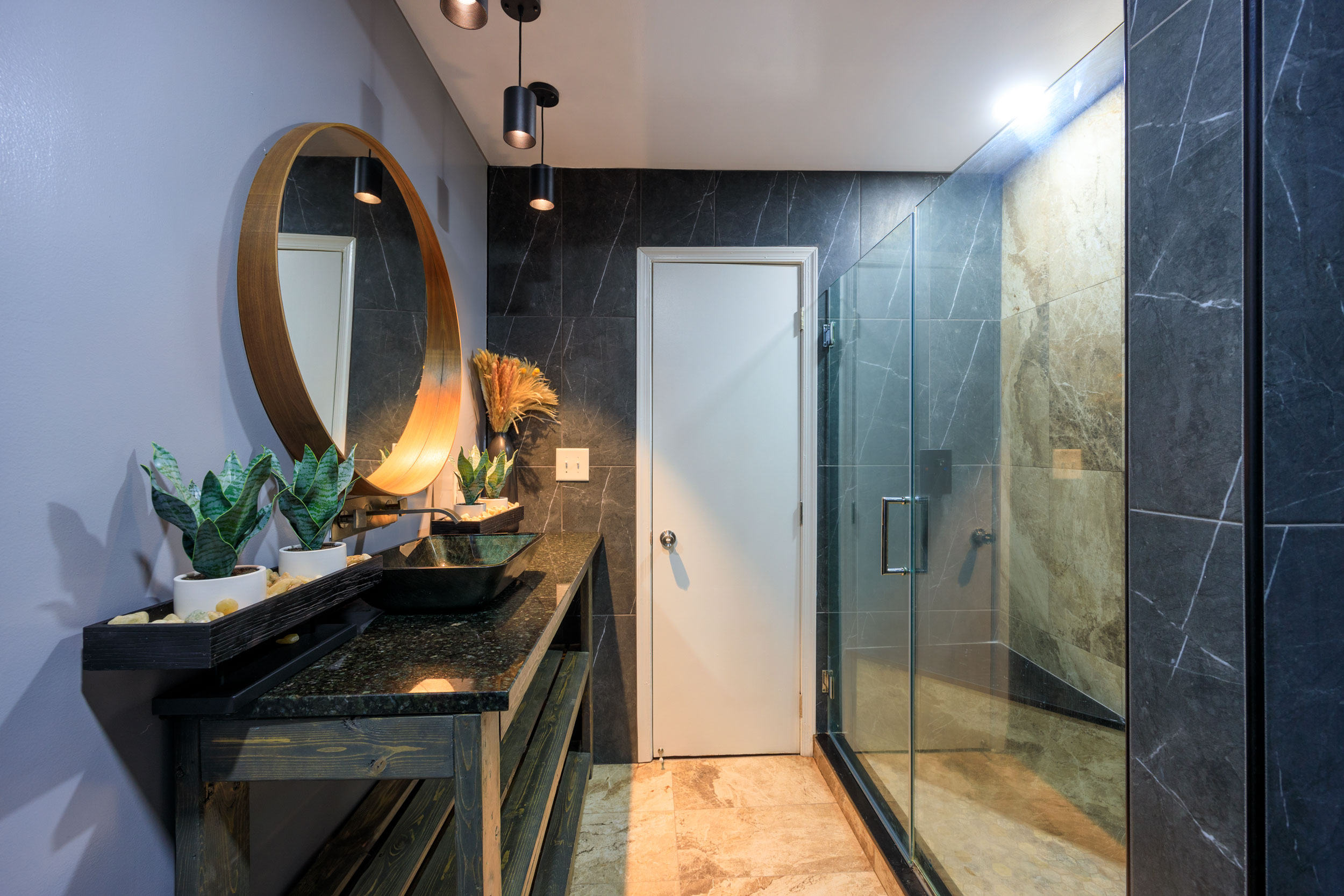 Modern bathroom remodeling in Bowie, MD featuring mosaic shower floor, black marble-look tile walls, granite vanity top, vessel sink, wall-mounted faucet, and rain shower by Zion Home Remodeling®, a top-rated Maryland bathroom remodeling contractor.