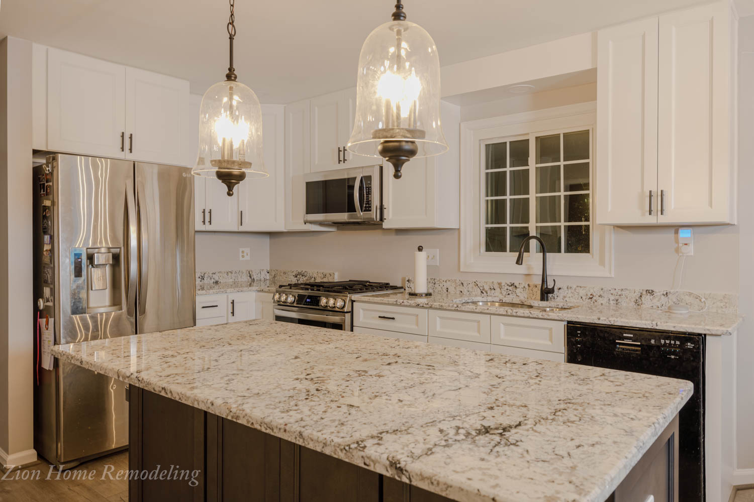 Modern kitchen with white base cabinets, gray island, granite countertop, vinyl plank flooring, and pendant light.