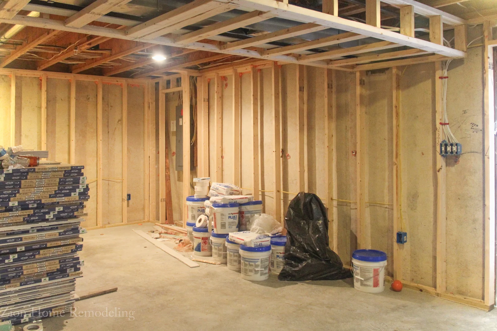 Basement Remodeling & Communication in Bowie, Columbia, and Silver Spring, MD Photo of a basement finishing project in Bowie, MD, US showing framed walls, rough-in electrical, fireblocking, joint compound buckets, and drywall sheets prepared for county inspection.