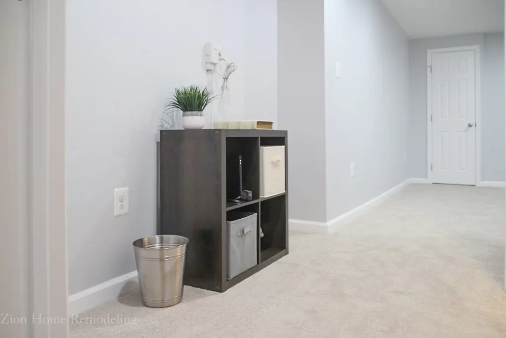 Basement Finishing Project in Bowie, MD Basement remodel in Bowie, MD, US showing hallway detail with gray walls, white ceiling, carpet flooring, and decorative furniture, highlighting expert basement finishing services by Zion Home Remodeling.