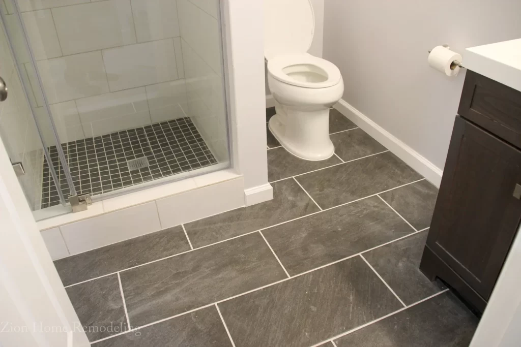 Finished basement bathroom in Bowie, Maryland, US with walk-in shower, tiled floor, new toilet, vanity, and shower door, remodeled by Zion Home Remodeling.