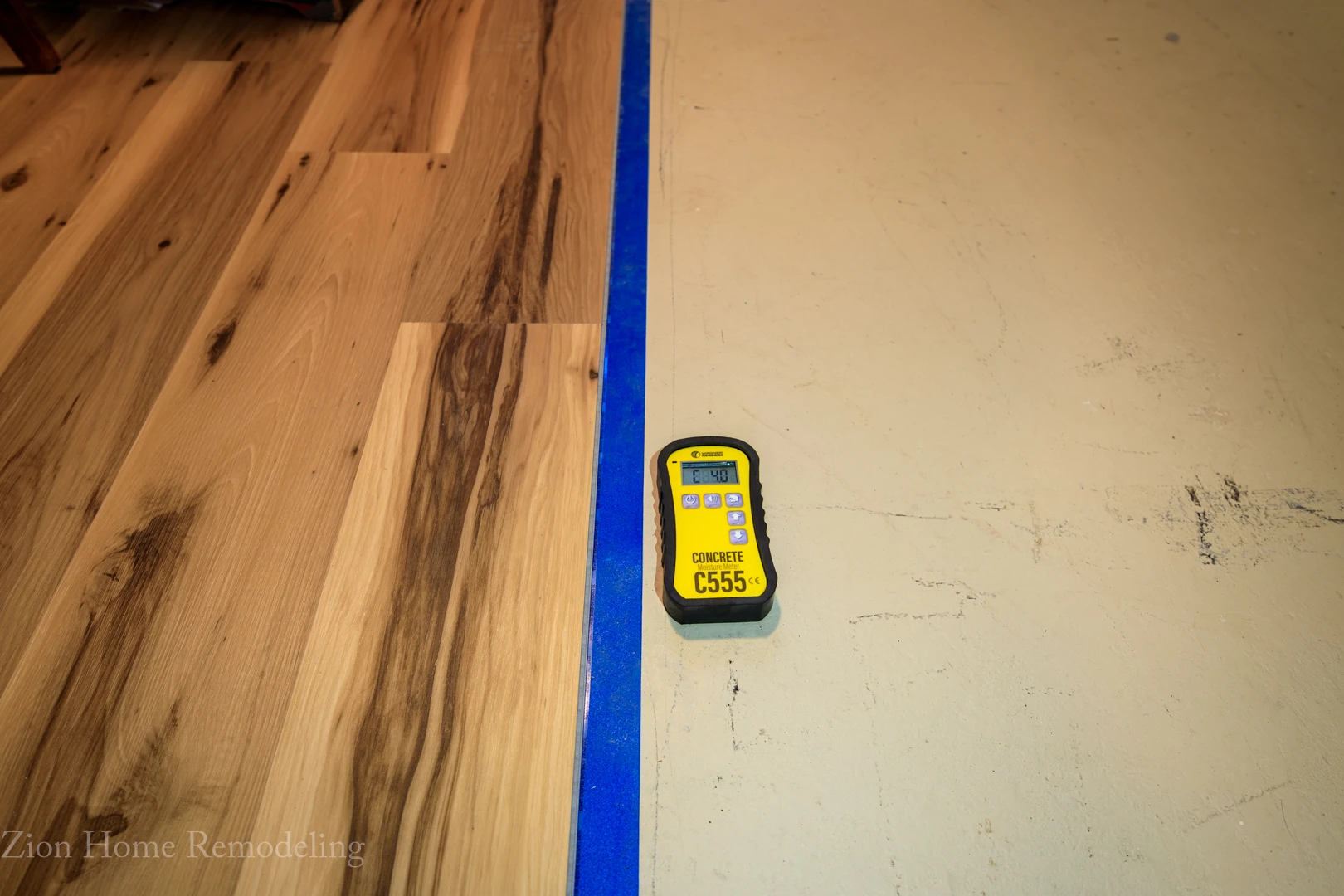 Basement flooring project in Cheverly, MD, US, showing concrete moisture reading C555 at 4.0 next to partially installed vinyl plank flooring and premium underlayment in Prince George’s County.